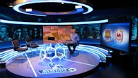 a man sits at a table in front of a television set