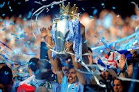 a group of manchester city fans holding up a trophy